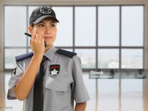 Security guard is talking with walkie talkie in her hand.